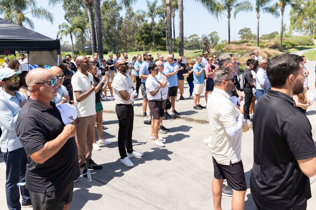 Tournament attendees stand at attention during the national anthem at Old Ranch Country Club