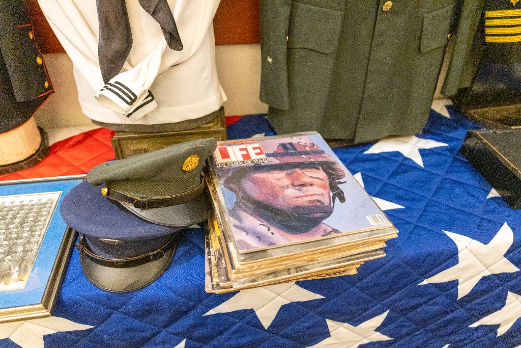 Military service caps and vintage Life magazine covers displayed on a star-spangled table